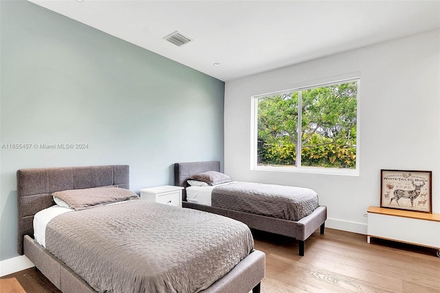 bedroom featuring visible vents, baseboards, and wood finished floors