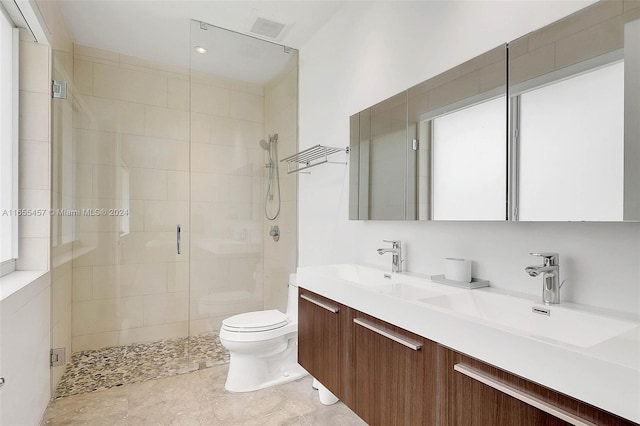 bathroom with a shower stall, double vanity, a sink, and toilet