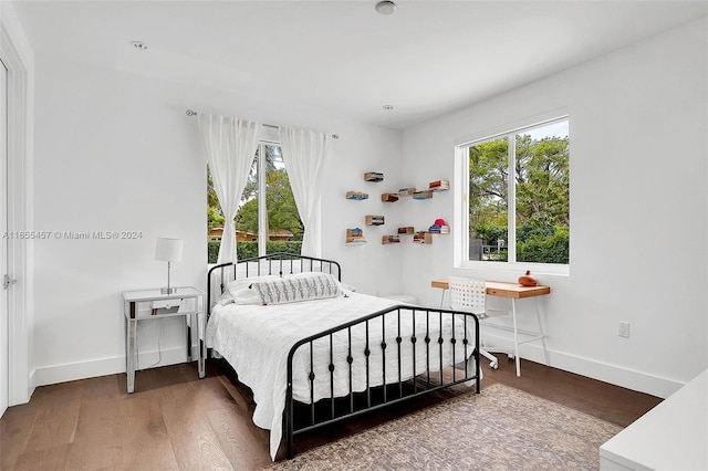 bedroom with multiple windows and dark hardwood / wood-style floors