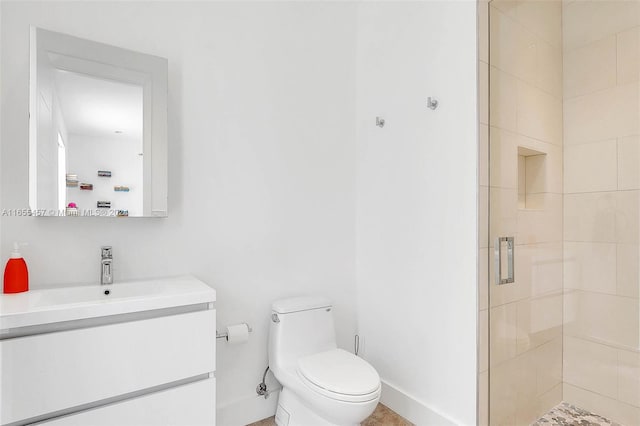 full bath featuring toilet, a shower stall, vanity, and baseboards