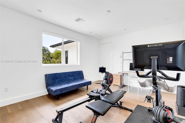 workout room featuring wood finished floors, baseboards, and visible vents