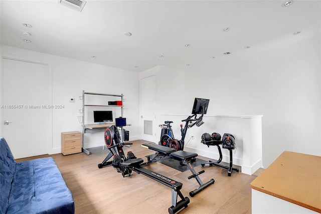 workout room with light wood finished floors, visible vents, and baseboards