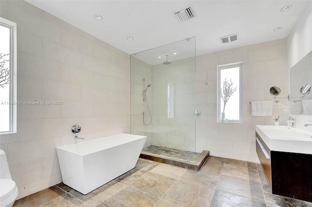 full bath featuring a walk in shower, vanity, visible vents, and tile walls