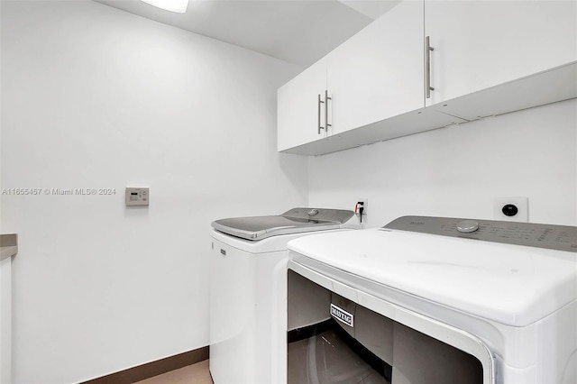 clothes washing area featuring independent washer and dryer, baseboards, and cabinet space
