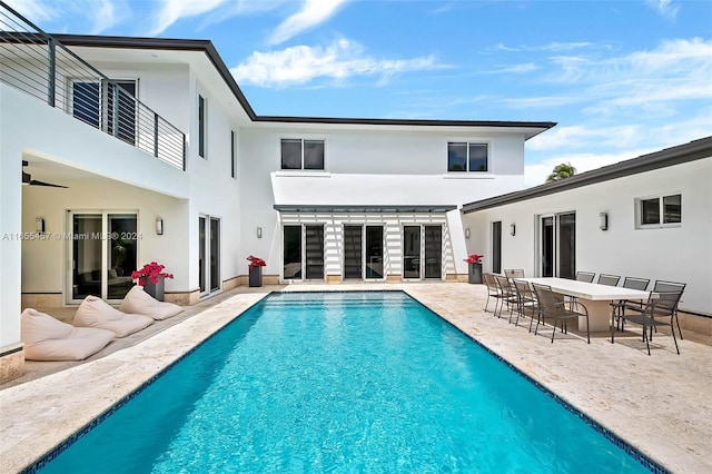 rear view of house with a patio, an outdoor pool, stucco siding, and a balcony