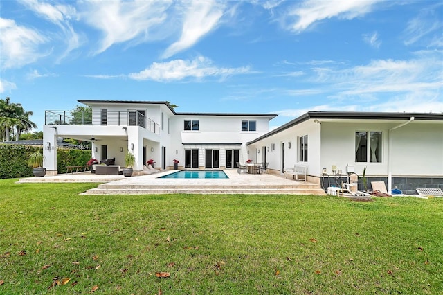 rear view of house featuring a patio area, a lawn, and a balcony