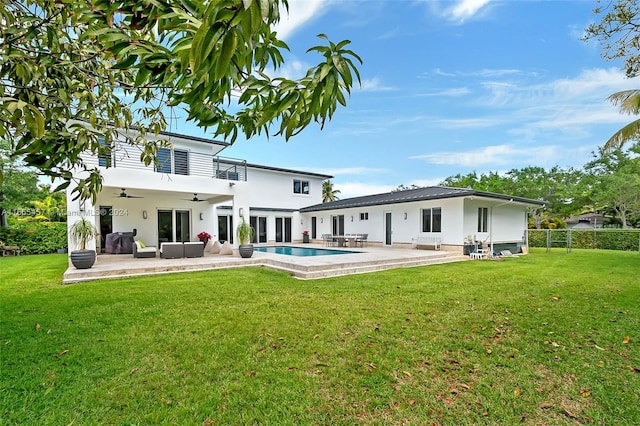 rear view of property with ceiling fan, outdoor lounge area, a fenced in pool, a patio area, and a lawn