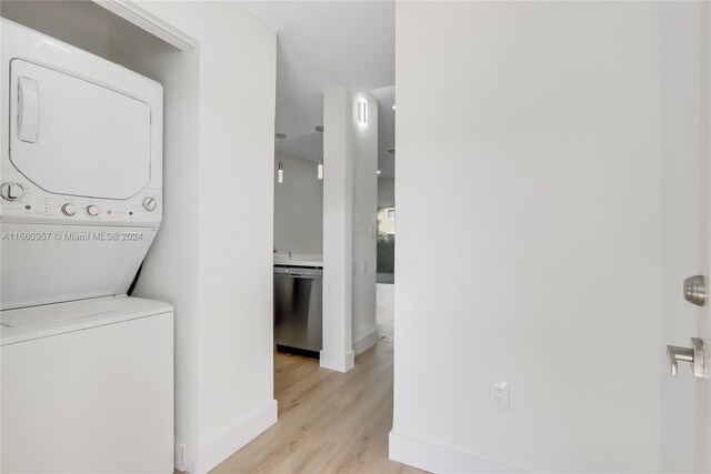 clothes washing area featuring stacked washer and dryer and light hardwood / wood-style flooring