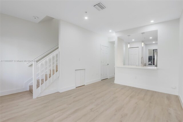 unfurnished living room featuring light hardwood / wood-style flooring and sink