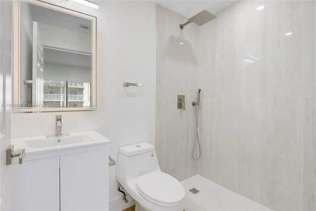 bathroom with a tile shower, vanity, and toilet