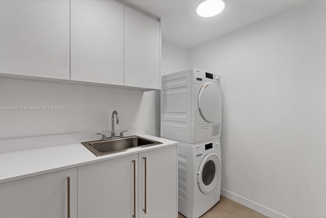 laundry area featuring cabinets, stacked washing maching and dryer, sink, and light tile patterned floors