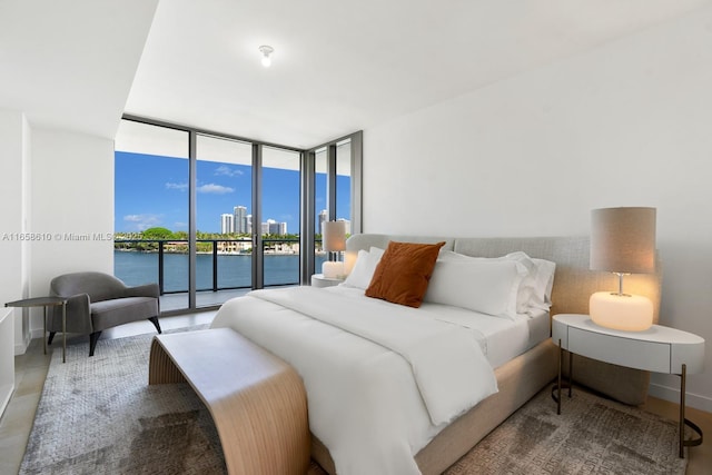 bedroom featuring access to exterior, floor to ceiling windows, and a water view