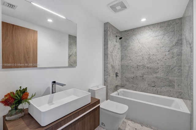 full bathroom with vanity, tiled shower / bath combo, and toilet