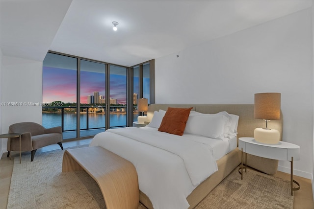 bedroom with a water view, expansive windows, and access to exterior