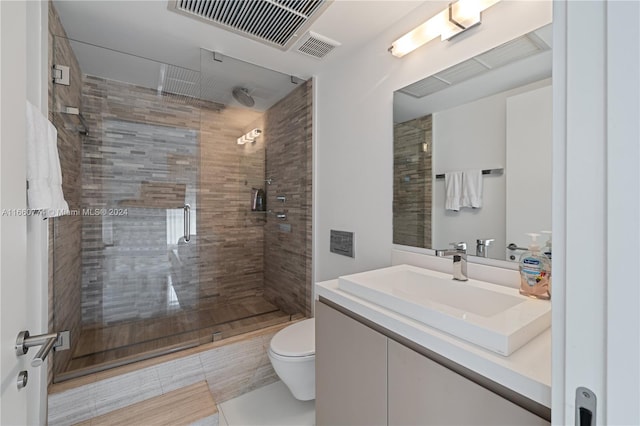 bathroom featuring vanity, toilet, and a shower with shower door