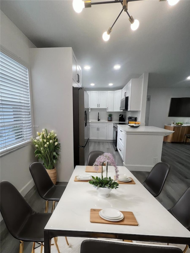 dining space featuring a notable chandelier, sink, and hardwood / wood-style floors