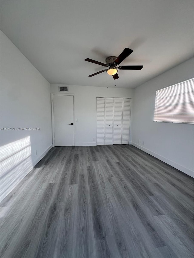 unfurnished bedroom featuring dark wood-type flooring, ceiling fan, and a closet