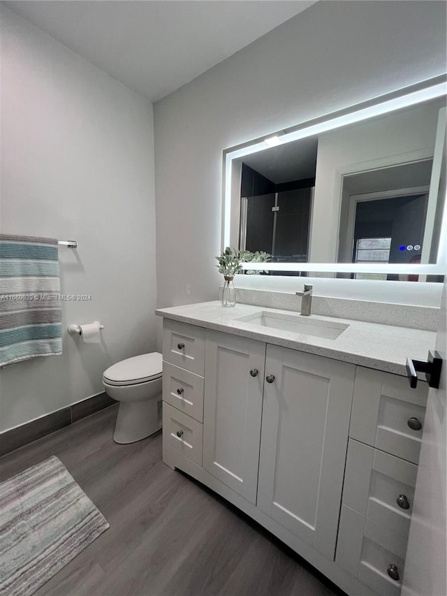 bathroom with vanity, toilet, and hardwood / wood-style floors