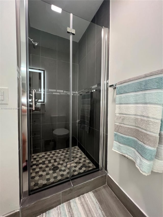 bathroom with toilet, hardwood / wood-style flooring, and a shower with door