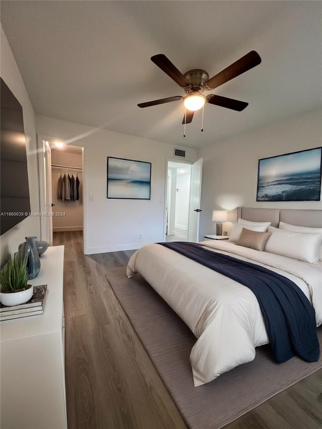 bedroom with a closet, ceiling fan, a walk in closet, and hardwood / wood-style floors