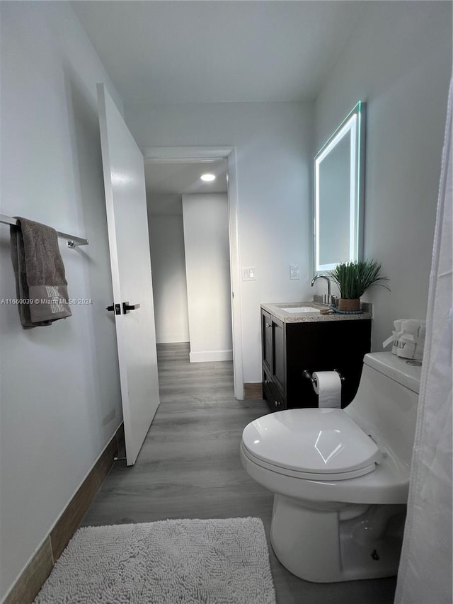 bathroom featuring toilet, hardwood / wood-style flooring, and vanity