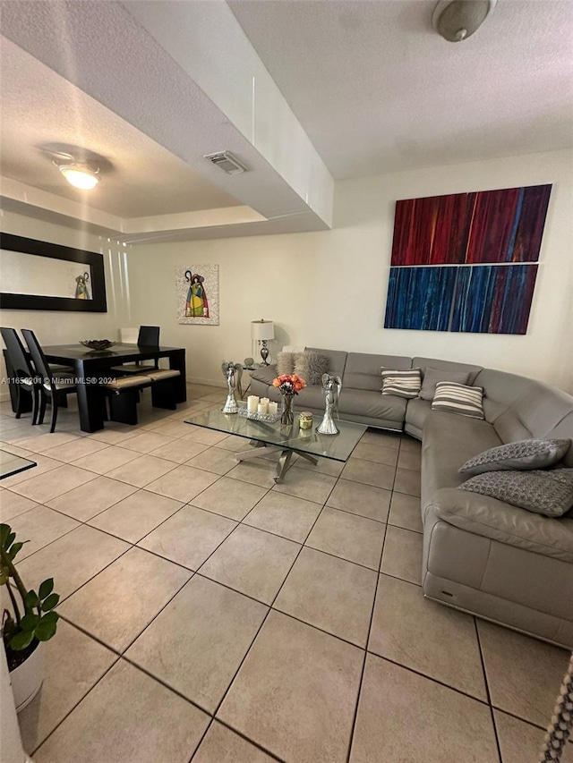 living room with a textured ceiling and light tile patterned flooring