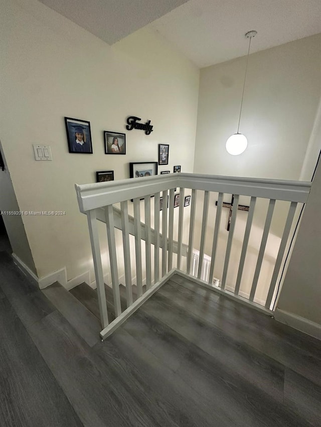 stairs featuring a textured ceiling, vaulted ceiling, and hardwood / wood-style floors