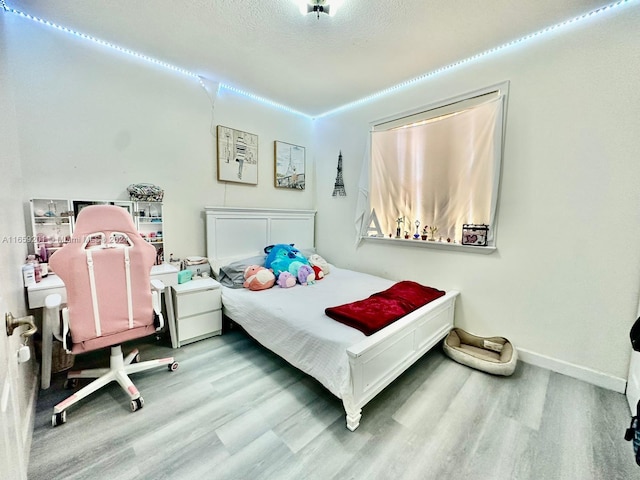 bedroom with a textured ceiling and light hardwood / wood-style floors