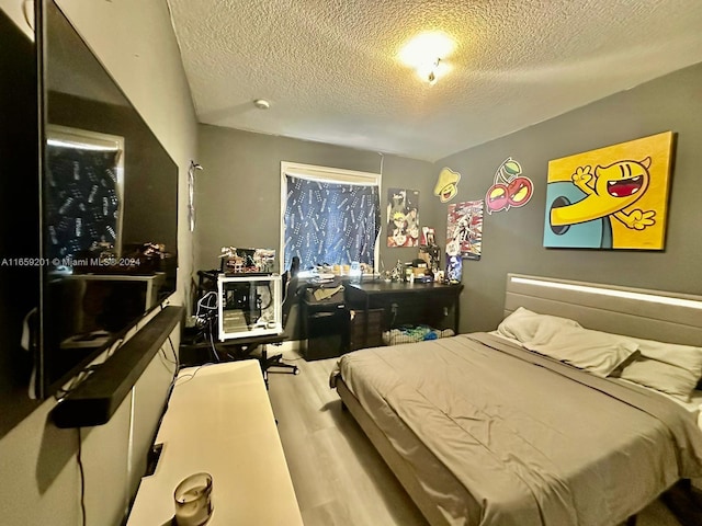 bedroom with a textured ceiling and light wood-type flooring