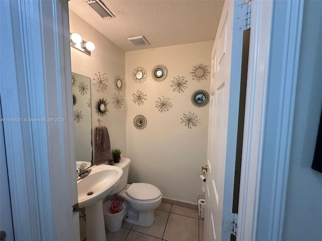 bathroom featuring a textured ceiling, tile patterned flooring, and toilet