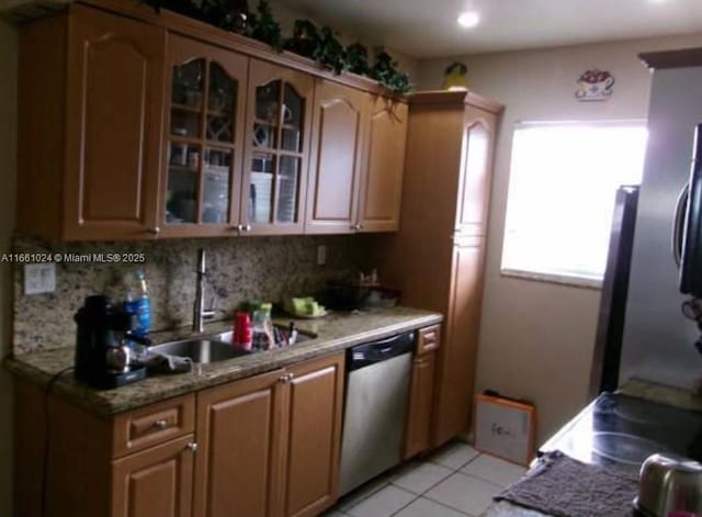 kitchen featuring sink, light tile patterned floors, tasteful backsplash, light stone countertops, and stainless steel dishwasher