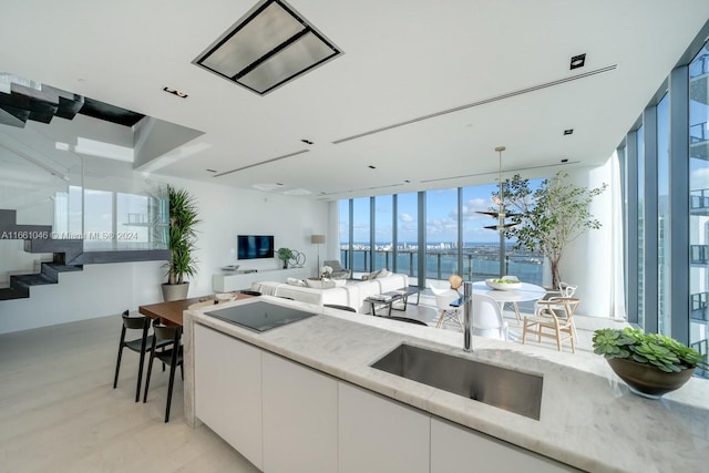 kitchen with expansive windows, sink, light hardwood / wood-style flooring, decorative light fixtures, and white cabinetry