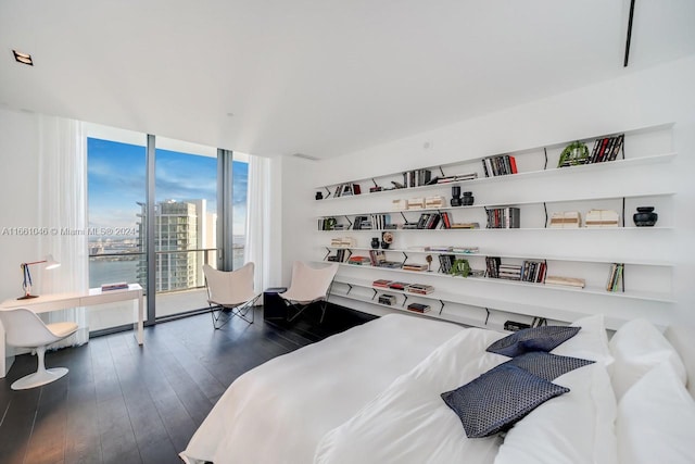 bedroom featuring expansive windows, dark hardwood / wood-style flooring, and a water view