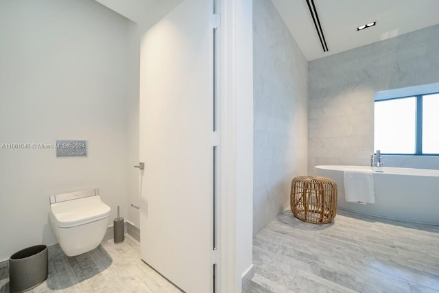 bathroom featuring tile walls, a bath, and toilet