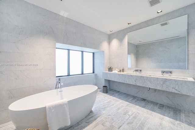 bathroom featuring vanity, a relaxing tiled tub, and tile walls