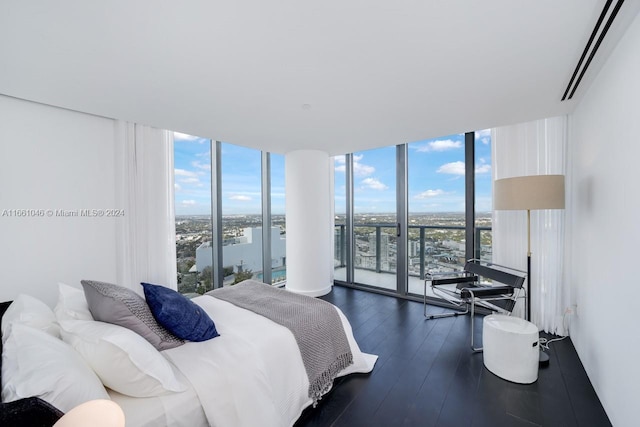 bedroom with a water view, a wall of windows, access to outside, and dark hardwood / wood-style flooring