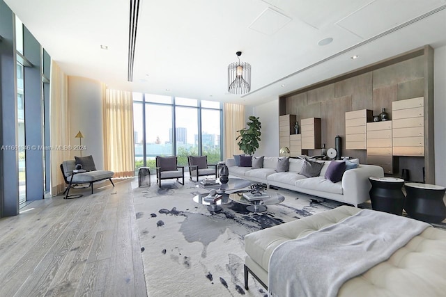 living room featuring an inviting chandelier, a wall of windows, and light wood-type flooring