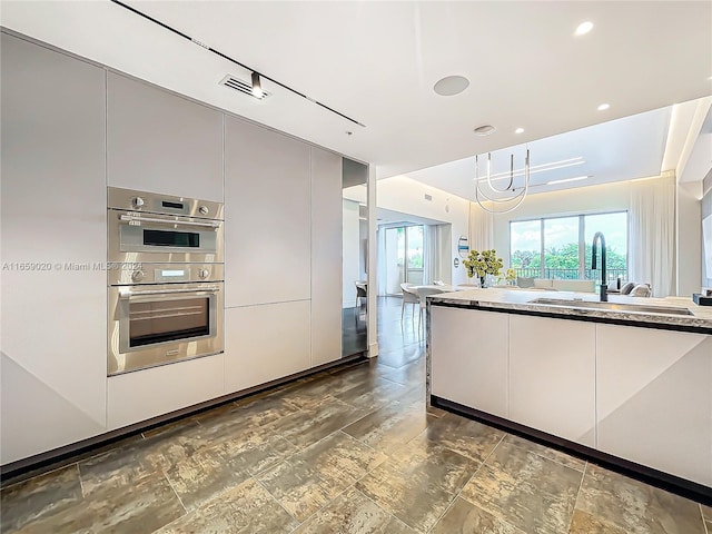 kitchen with double oven, a chandelier, and sink