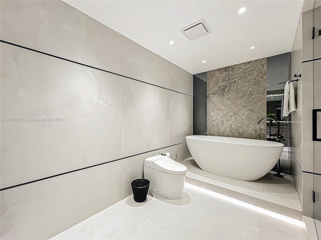 bathroom featuring a tub to relax in, tile walls, and toilet