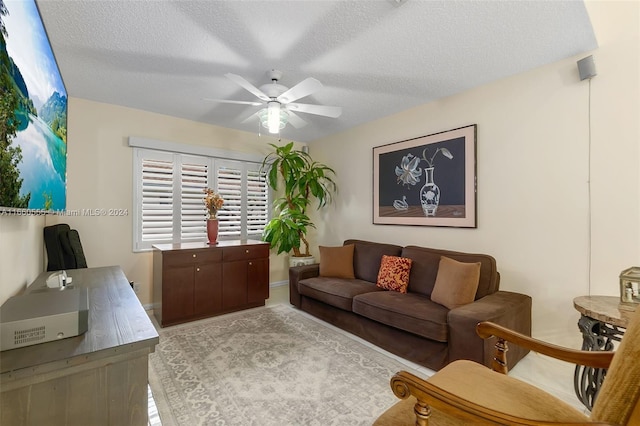 living room with a textured ceiling, light hardwood / wood-style floors, and ceiling fan