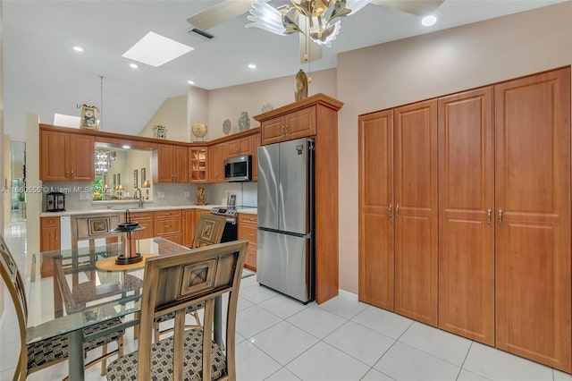 kitchen featuring ceiling fan, a skylight, light tile patterned floors, tasteful backsplash, and appliances with stainless steel finishes