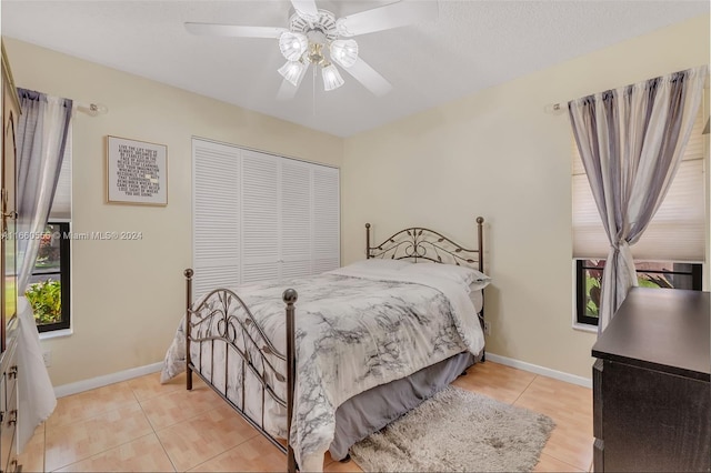 tiled bedroom with ceiling fan and a closet