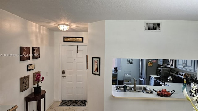 tiled foyer entrance with a textured ceiling and sink