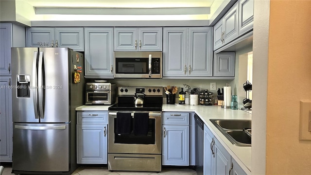 kitchen featuring gray cabinets, stainless steel appliances, light tile patterned floors, and sink