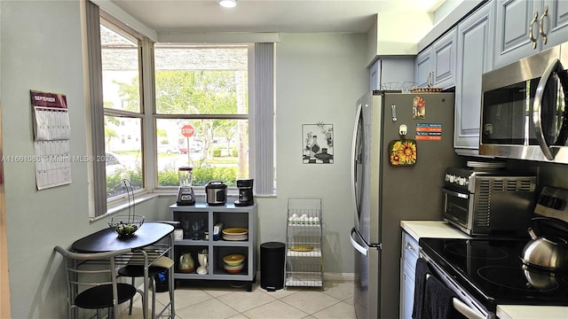 kitchen featuring gray cabinetry, appliances with stainless steel finishes, and light tile patterned floors