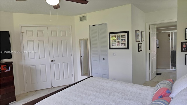 tiled bedroom with ceiling fan and two closets