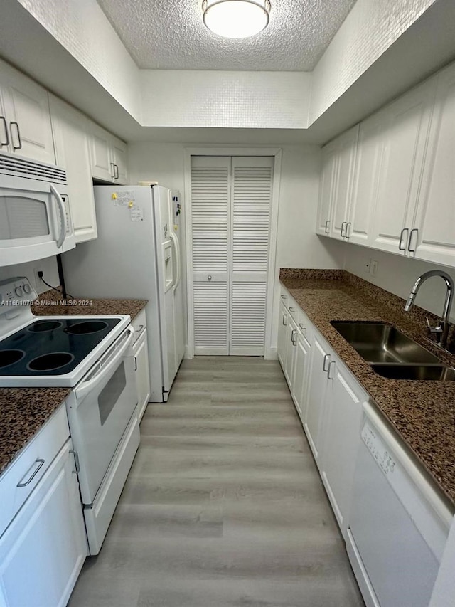 kitchen featuring sink, white appliances, a textured ceiling, light hardwood / wood-style flooring, and white cabinetry