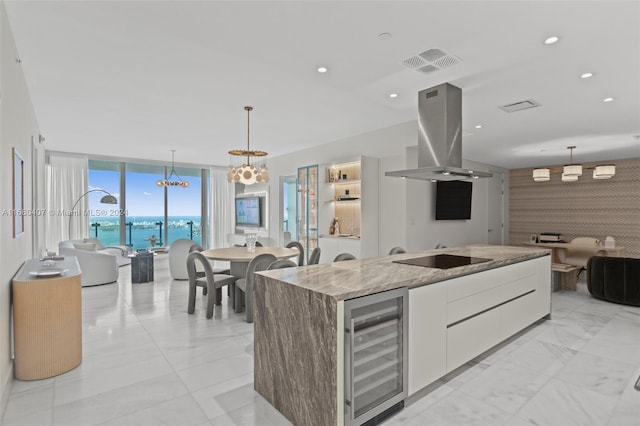 kitchen featuring wine cooler, a kitchen island, island exhaust hood, white cabinetry, and a water view