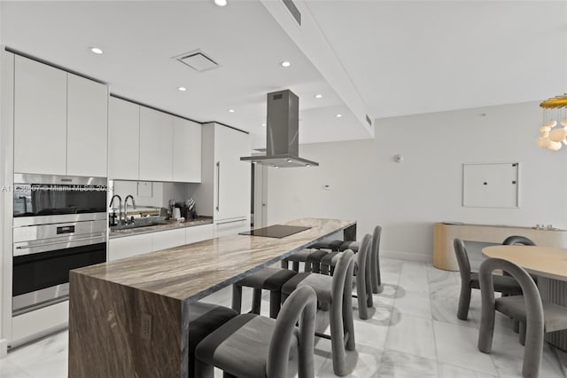 kitchen featuring white cabinetry, island range hood, a center island, and sink