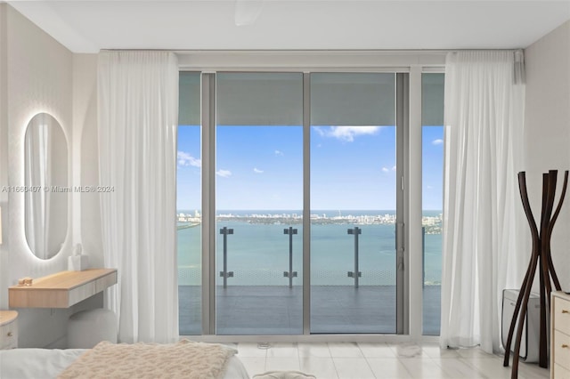 bedroom featuring multiple windows, a water view, and floor to ceiling windows